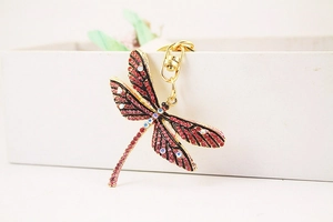 Detailed close-up of a golden dragonfly keychain set with red and purple rhinestones