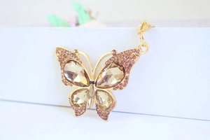 Macro detail of gold butterfly pendant with champagne crystals and rhinestone inlay