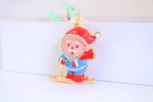 Detail of metal skiing Santa Claus keychain with red enamel and sparkling rhinestones