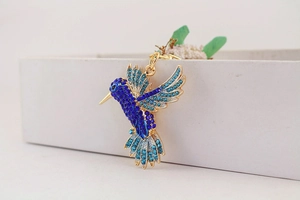 Vue détaillée d'un pendentif colibri en strass colorés avec cristaux bleus et dorures