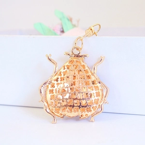 Close-up of golden ladybug keychain with hollow clover patterns and lobster clasp