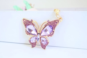 Macro shot of purple crystal butterfly charm with teardrop stones and gold-plated details