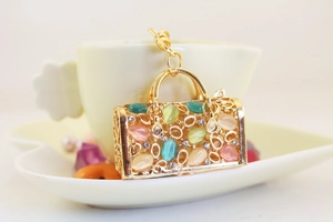 Detailed close-up of a gold handbag keychain featuring colorful opal stones and crystals