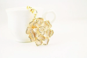 Detailed close-up of rose keychain with cream enamel petals and crystal rhinestones