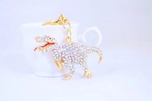 Close-up of a rhinestone dinosaur keychain with gold-plated lobster clasp detail