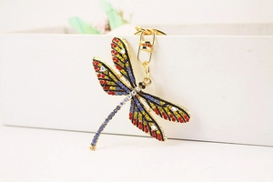 Detailed macro view of gold dragonfly keychain featuring vibrant multicolor crystals