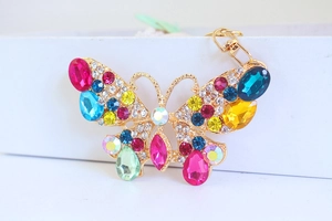 Dettaglio portachiavi a farfalla con strass multicolori e base in metallo dorato