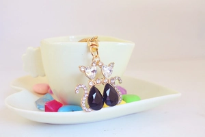 Detail shot of a couple cat keychain with black stones and heart zircons in gold
