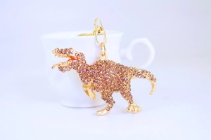 Detailed close-up of a sparkling rhinestone-studded dinosaur keychain with golden hardware