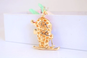 Close-up of golden metal skier pendant with hollow heart patterns on white display box