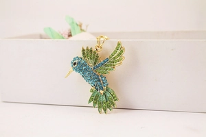 Détail du pendentif colibri avec strass bleus et verts sur un alliage doré élégant