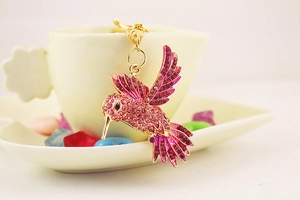 Détail du porte-clés colibri rose serti de cristaux sur le bord d'une tasse