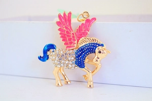 Dettaglio del portachiavi Pegaso dorato con ali in smalto rosa e strass blu brillanti