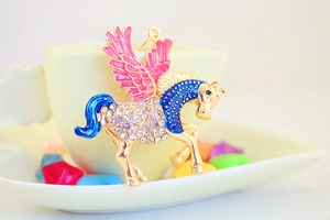 Dettaglio portachiavi pegaso dorato con ali in smalto rosa e strass luccicanti