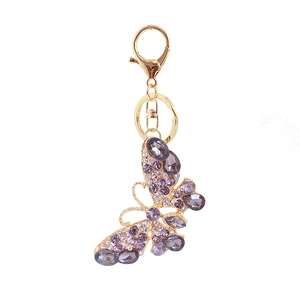 Portachiavi farfalla dorato con strass viola e chiusura a moschettone su sfondo bianco