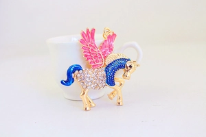 Dettaglio del portachiavi pegaso dorato con ali in smalto rosa e strass lucidi