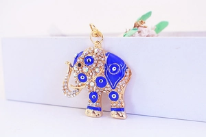 Macro shot of gold-plated elephant pendant with white crystals and blue evil eye enamel detail