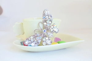 Dettaglio macro del portachiavi a farfalla con strass colorati e ali in lega d'argento