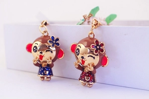 Detailed view of monkey pendant earrings with floral accents and colorful enamel coating
