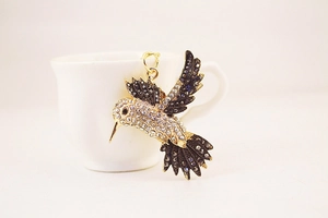 Détail d'un pendentif colibri avec cristaux suspendu au bord d'une tasse blanche