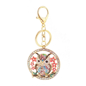 Golden owl keychain with colorful rhinestones and pink flowers on a white background