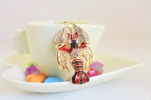 Détail macro du porte-clés homard en cristal suspendu sur le bord d'une tasse blanche