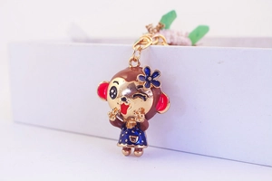 Detailed macro view of a cute cartoon monkey keychain with blue enamel dress and D-ring