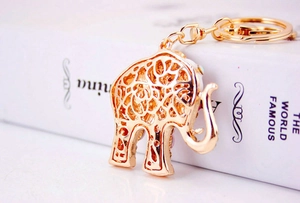 Close-up of golden elephant keychain with colorful crystals on a white background