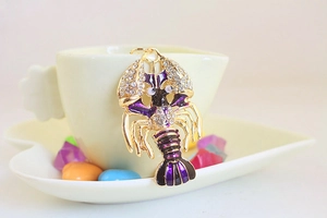 Détail du porte-clés homard doré avec émail violet et cristaux brillants sur une tasse