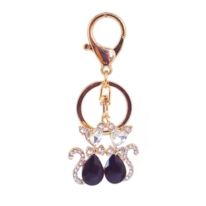 Golden double cat keychain with heart crystal and black teardrop gemstones on white back