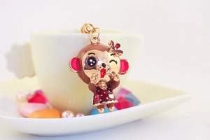 Detailed close-up of a cute monkey charm with red floral accents on a ceramic cup