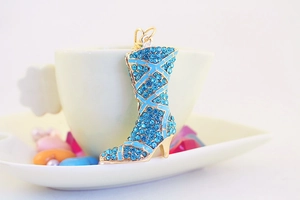 Close-up of a blue rhinestone encrusted boot charm on a cream ceramic coffee cup