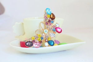 Dettaglio di un portachiavi a farfalla con strass colorati su una tazzina