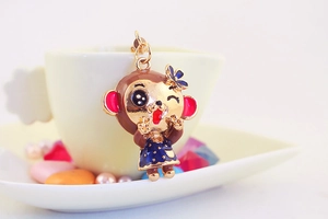 Cute monkey pendant with blue dress hanging on a white ceramic cup for keychains