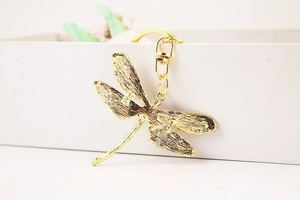 Macro shot of golden dragonfly keychain featuring detailed mesh texture and lobster clasp