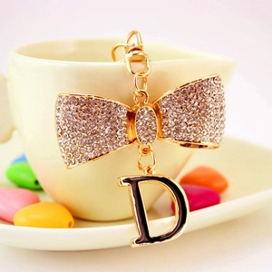 Porte-clés chic doré avec nœud en strass et pendentif lettre D en émail noir