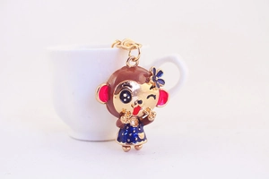Detail of cute monkey keychain with blue flower and enamel finish on white background