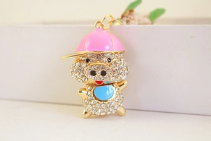 Détail d'un porte-clés cochon doré avec casquette rose et ventre en émail bleu ciel