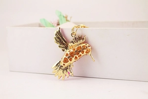 Gros plan détaillé d'un porte-clés colibri doré avec cœur évidé et touches d'émail rose