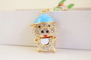 Détail de porte-clés cochon doré avec cristaux blancs et petite casquette de baseball bleue