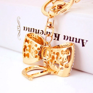Porte-clés nœud doré évidé avec pendentif lettre D orné de strass brillants
