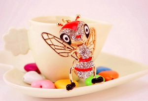 Détail du porte-clés abeille dorée avec cristaux brillants et émail rouge élégant