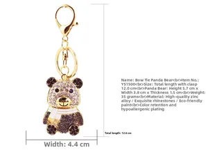 Dettaglio ravvicinato di un portachiavi a panda dorato con strass neri e bianchi su fondo bianco