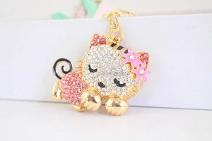 Macro view of sparkling rhinestone sleeping cat keychain with pink enamel flowers