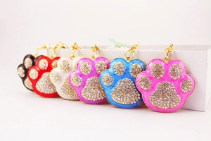Close-up of sparkling rhinestone paw print keychains in six vibrant colors with gold lobster clasps