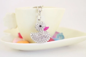 Dettaglio di un portachiavi a forma di anatra con strass appeso a una tazzina da caffè