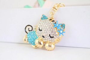 Macro detail of a sleeping cat keychain with inlaid blue rhinestones and gold-plated finish