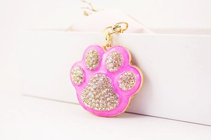 Close-up of pink paw keychain with white rhinestones and a gold alloy clasp detail