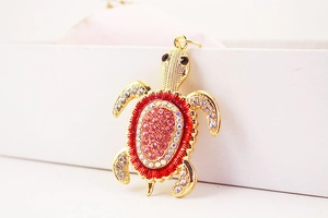 Détail du porte-clés tortue dorée serti de strass roses et rouges et cristaux étincelants