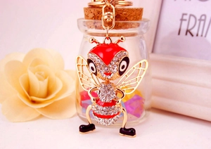 Détail macro d'un porte-clés abeille en cristal avec émail rouge et cadre en métal doré